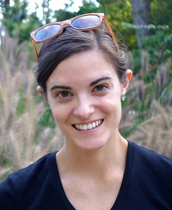 Corlett Wood outside with sunglasses on her head smiling at the camera